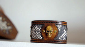 Website videos. A close up shot of the finished leather bracelet featuring a gold metal skull.