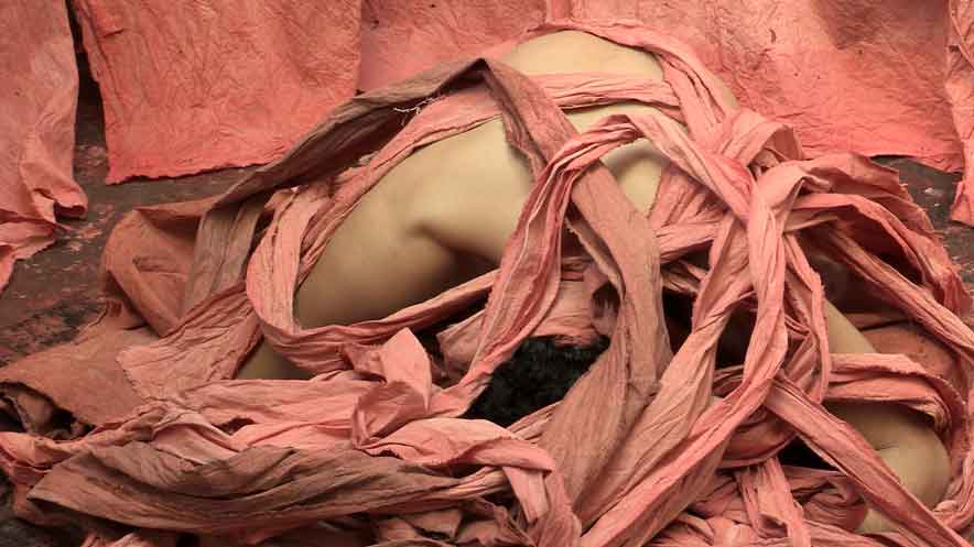 Dance video featuring Dane Jeremy Hurst is curled up on the floor in a bed of pink dyed cloth costumes