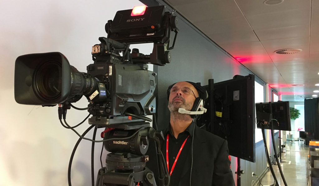 Corporate filming by London based cameraman Julian Langham seen looking up through the camera top mounted monitor