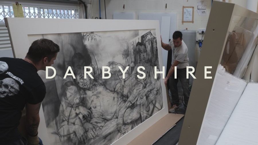 Workshop promotional video for Darbyshire Framers. Two men hold a large artwork frame at each end showing a monochrome contemporary drawing with white text overlay