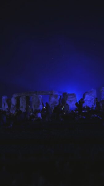 Stonehenge solstice 2026 - the stones at night partially lit by blue floodlights